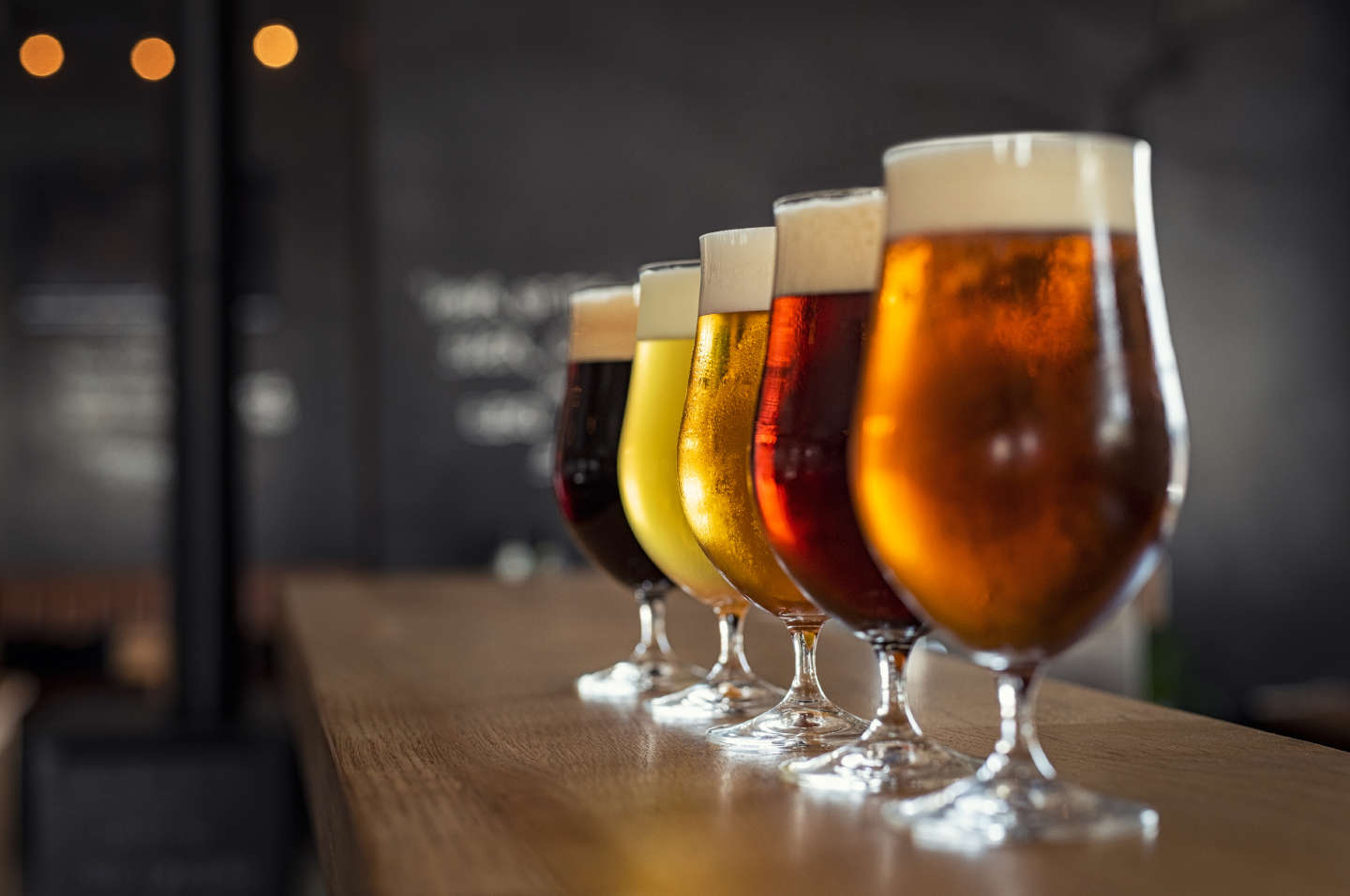 assorted beers lined up in stemmed glassware